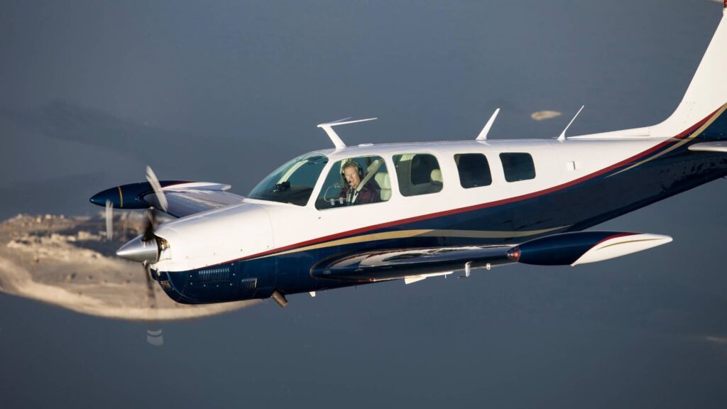 Avião monomotor Bonanza em voo.